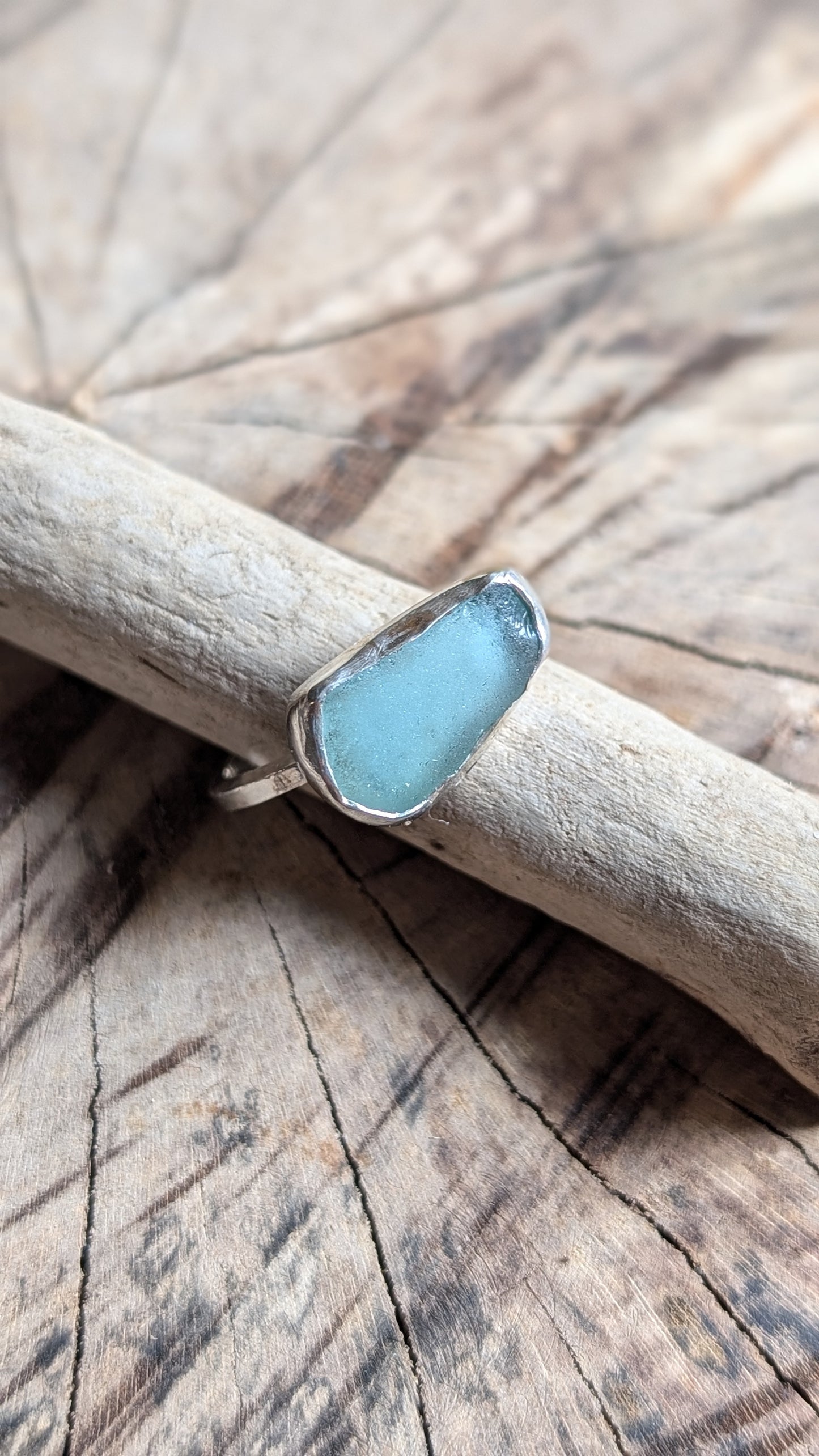 Adjustable blue sea glass ring encased in silver bezel