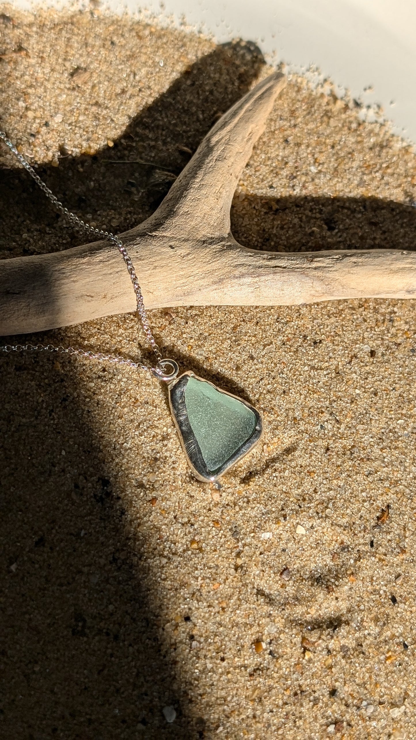 Sea foam sea glass pendant encased in open backed bezel with chain