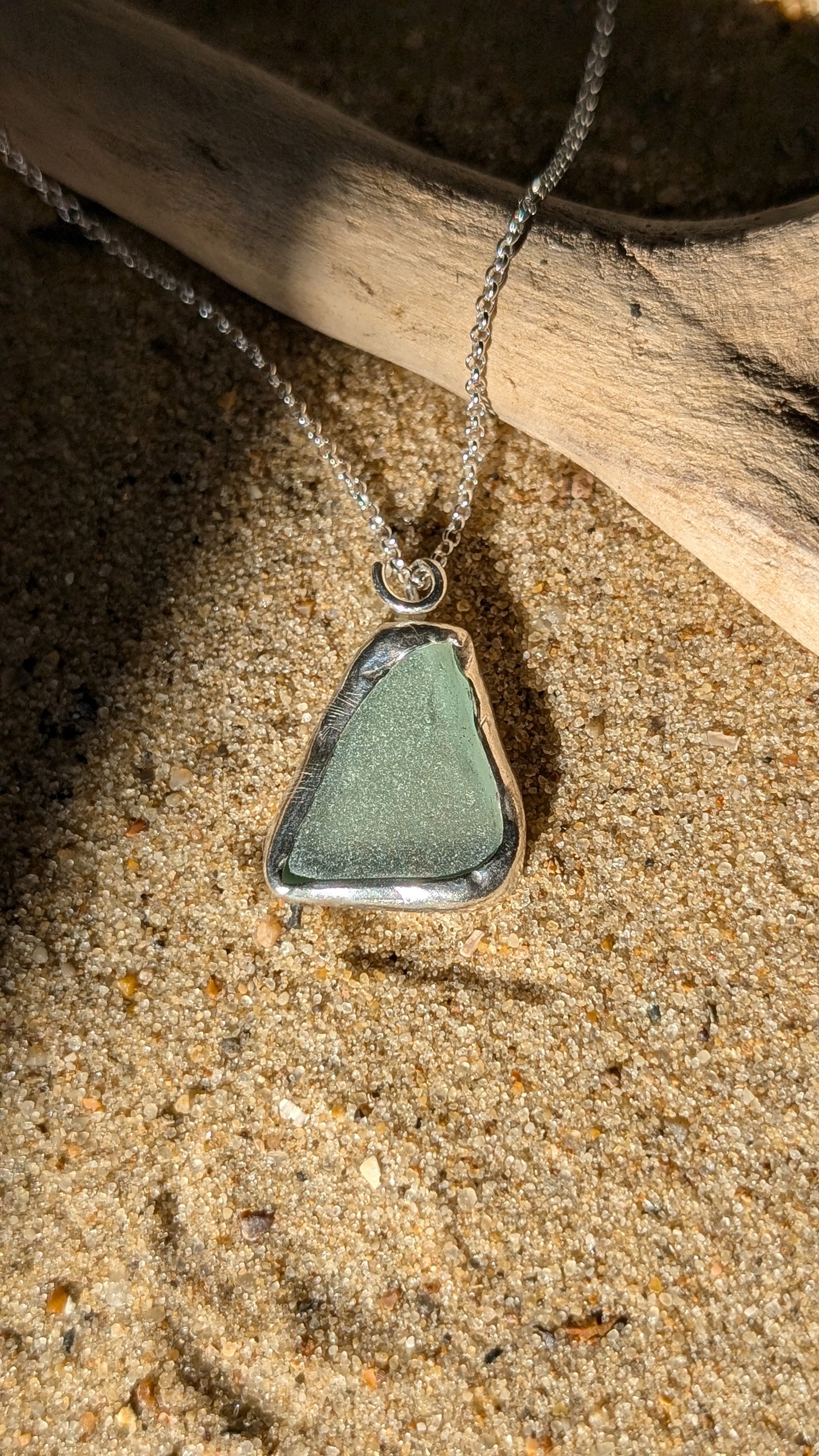 Sea foam sea glass pendant encased in open backed bezel with chain