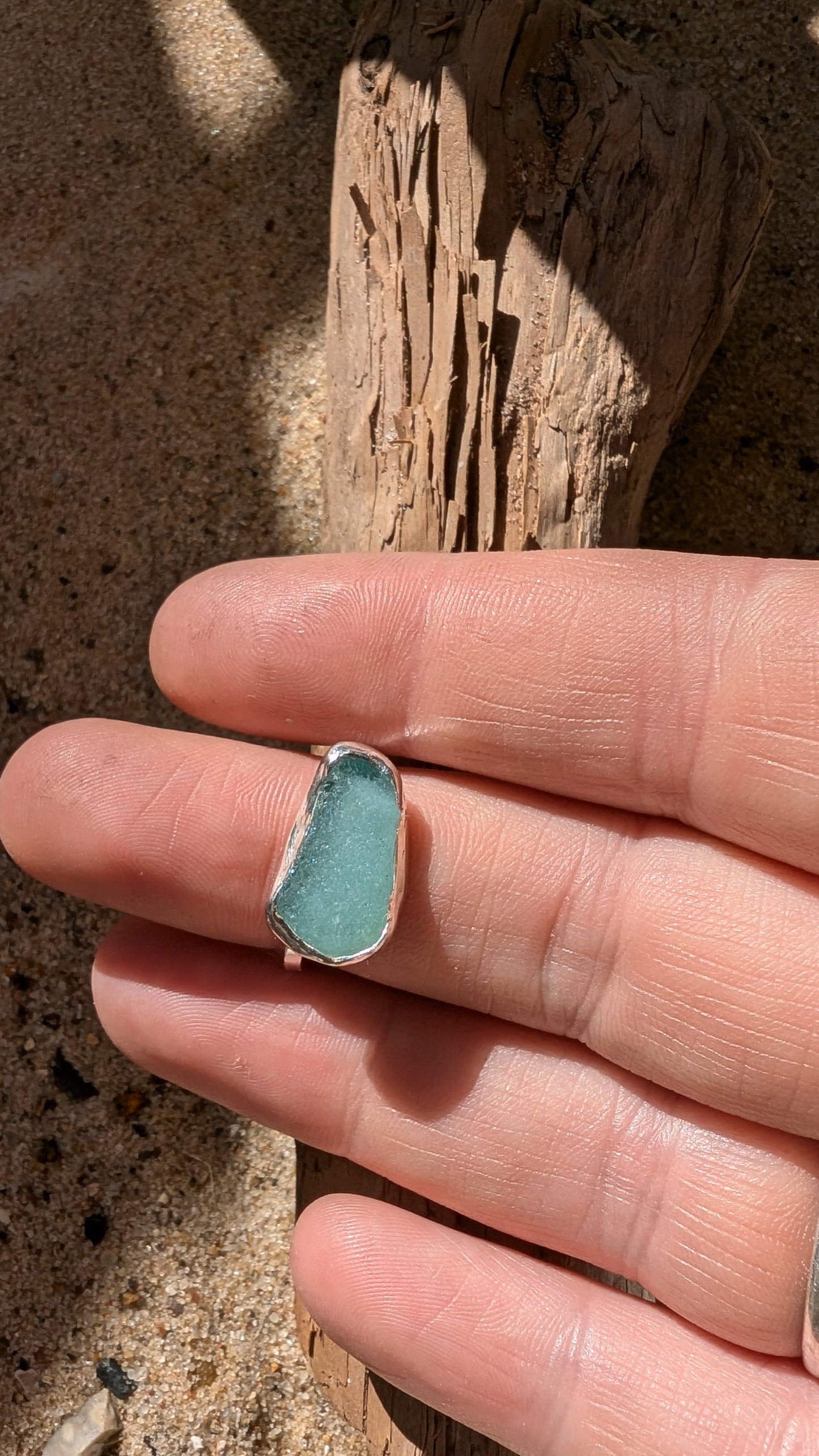 Adjustable blue sea glass ring encased in silver bezel