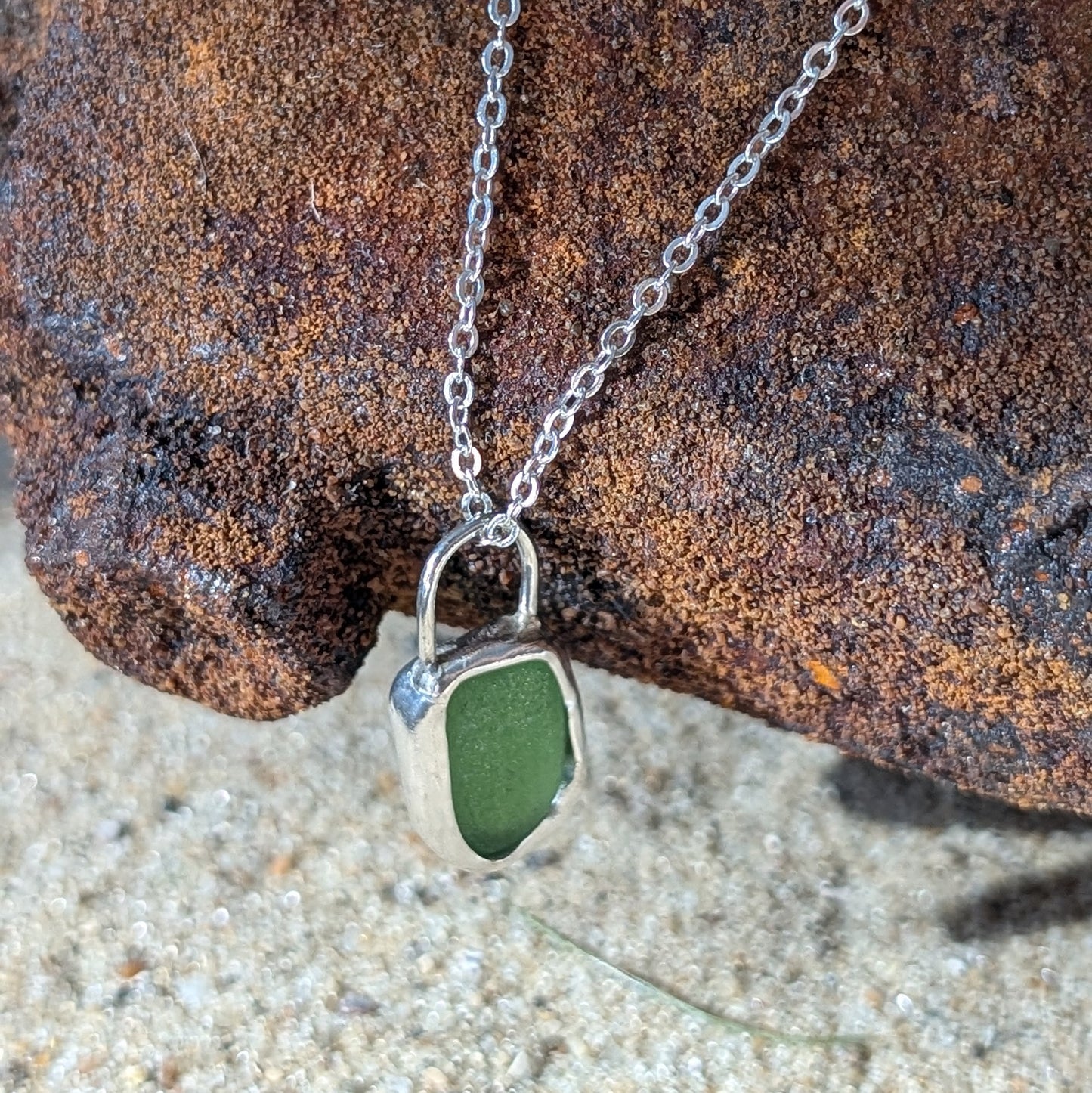 Green sea glass pendant encased in open backed bezel with chain