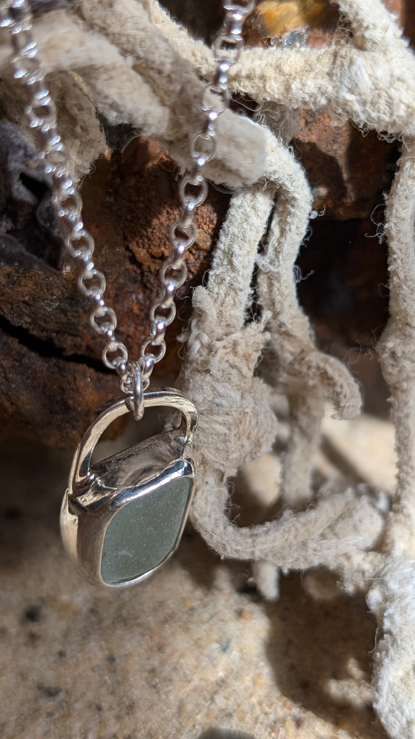 Sea foam sea glass pendant encased in open backed bezel with chain