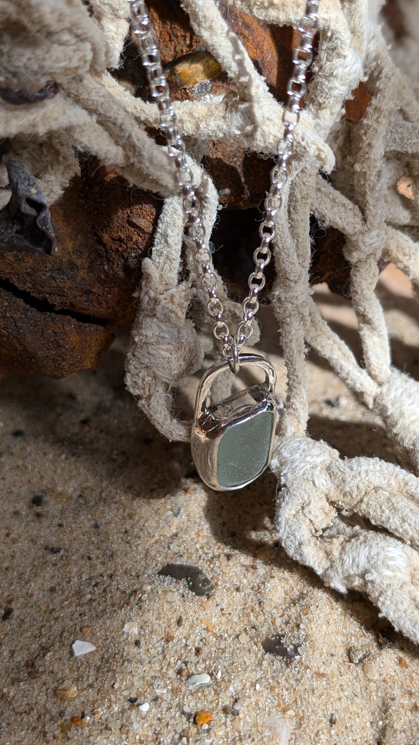 Sea foam sea glass pendant encased in open backed bezel with chain