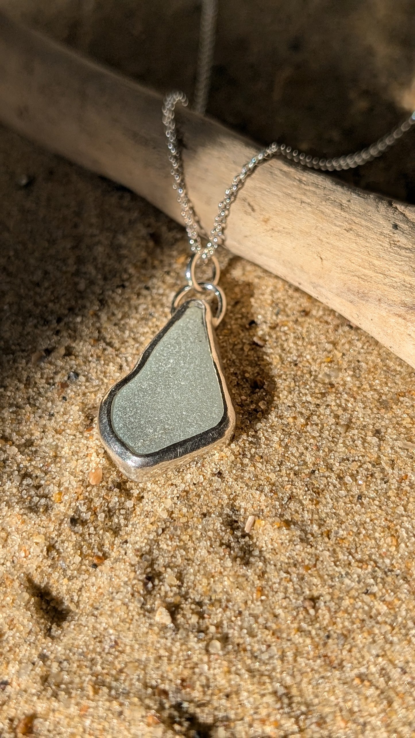 White sea glass pendant encased in open backed bezel with chain