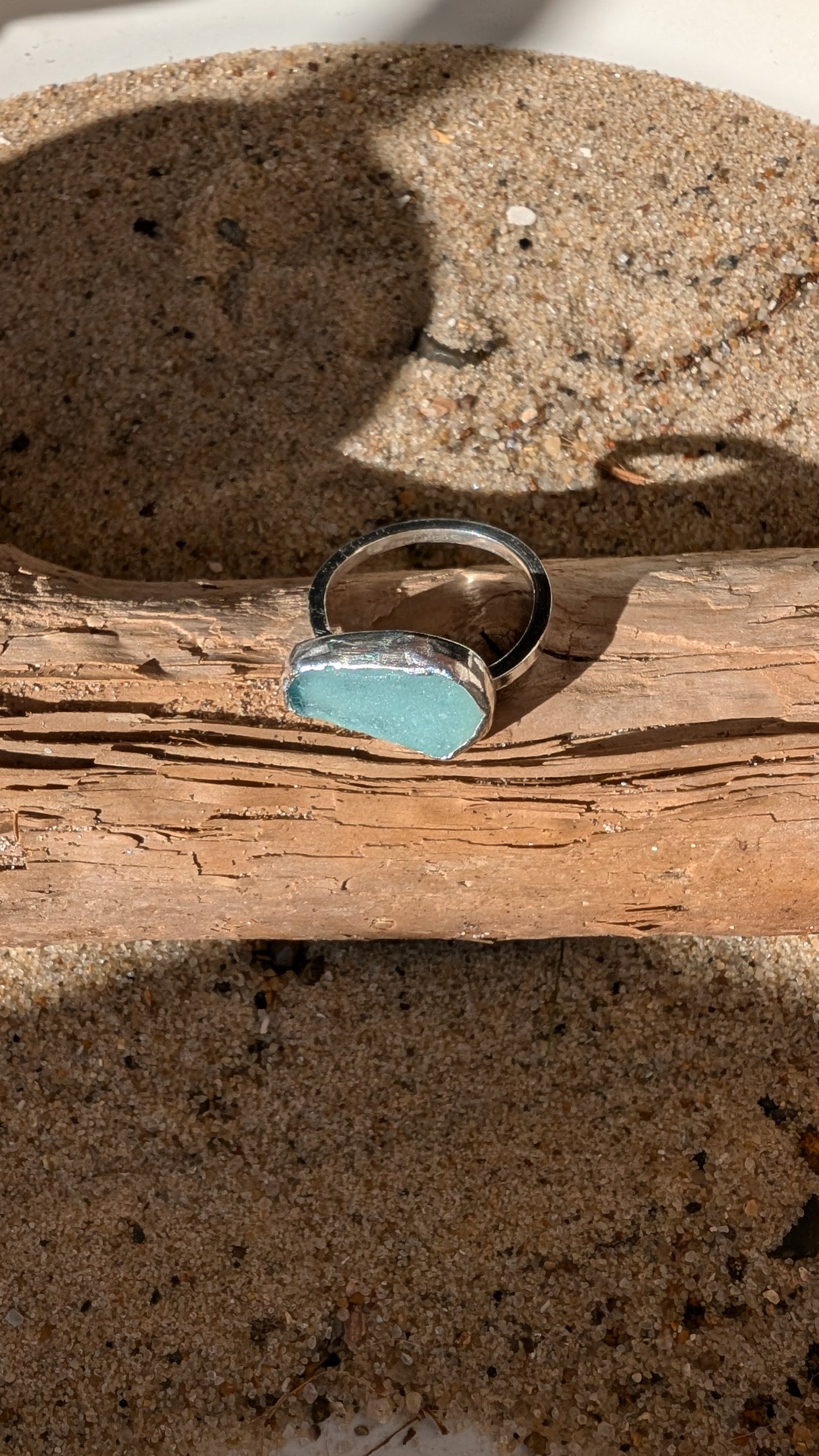 Adjustable blue sea glass ring encased in silver bezel