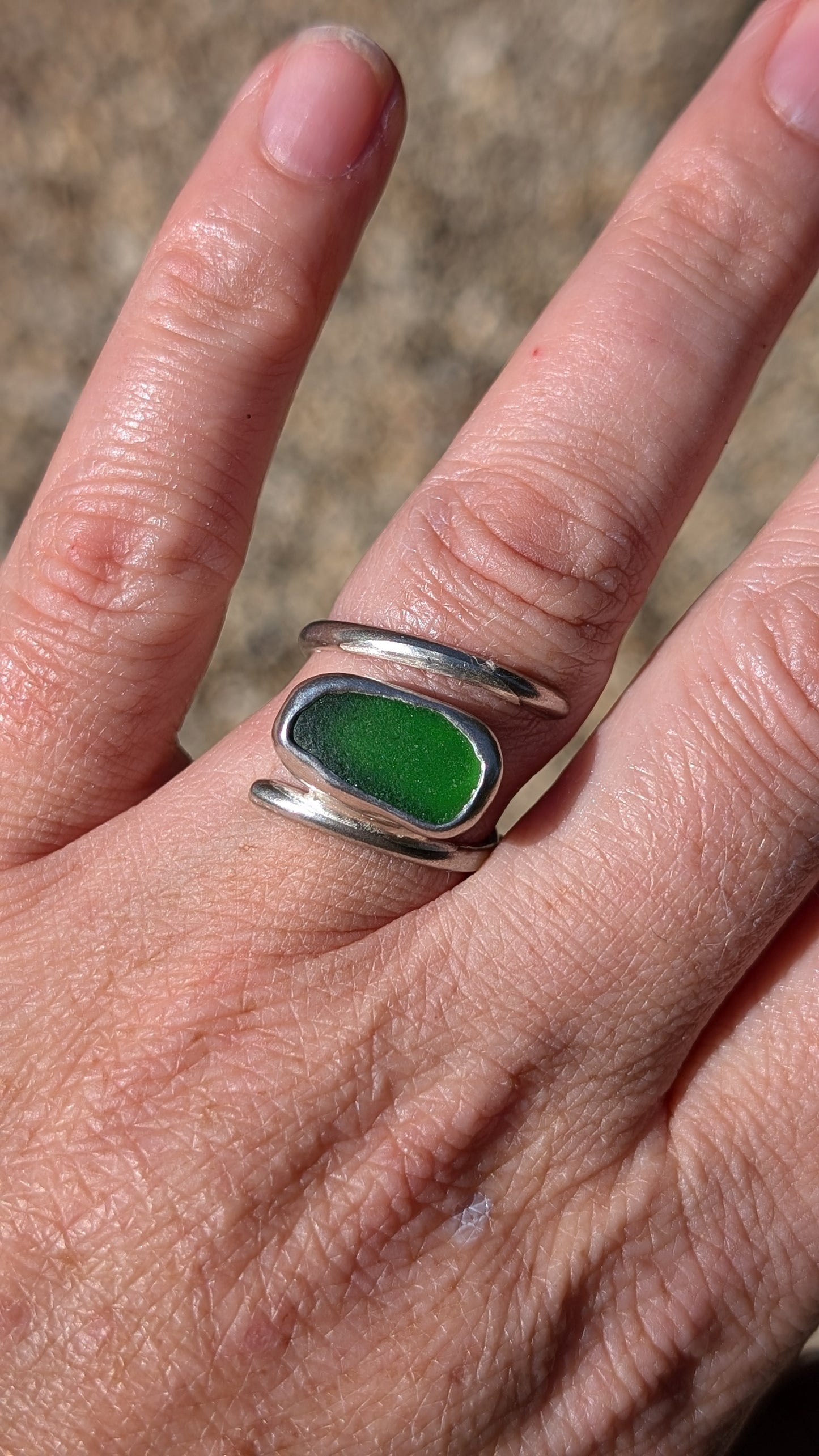 Adjustable green sea glass ring encased in silver bezel