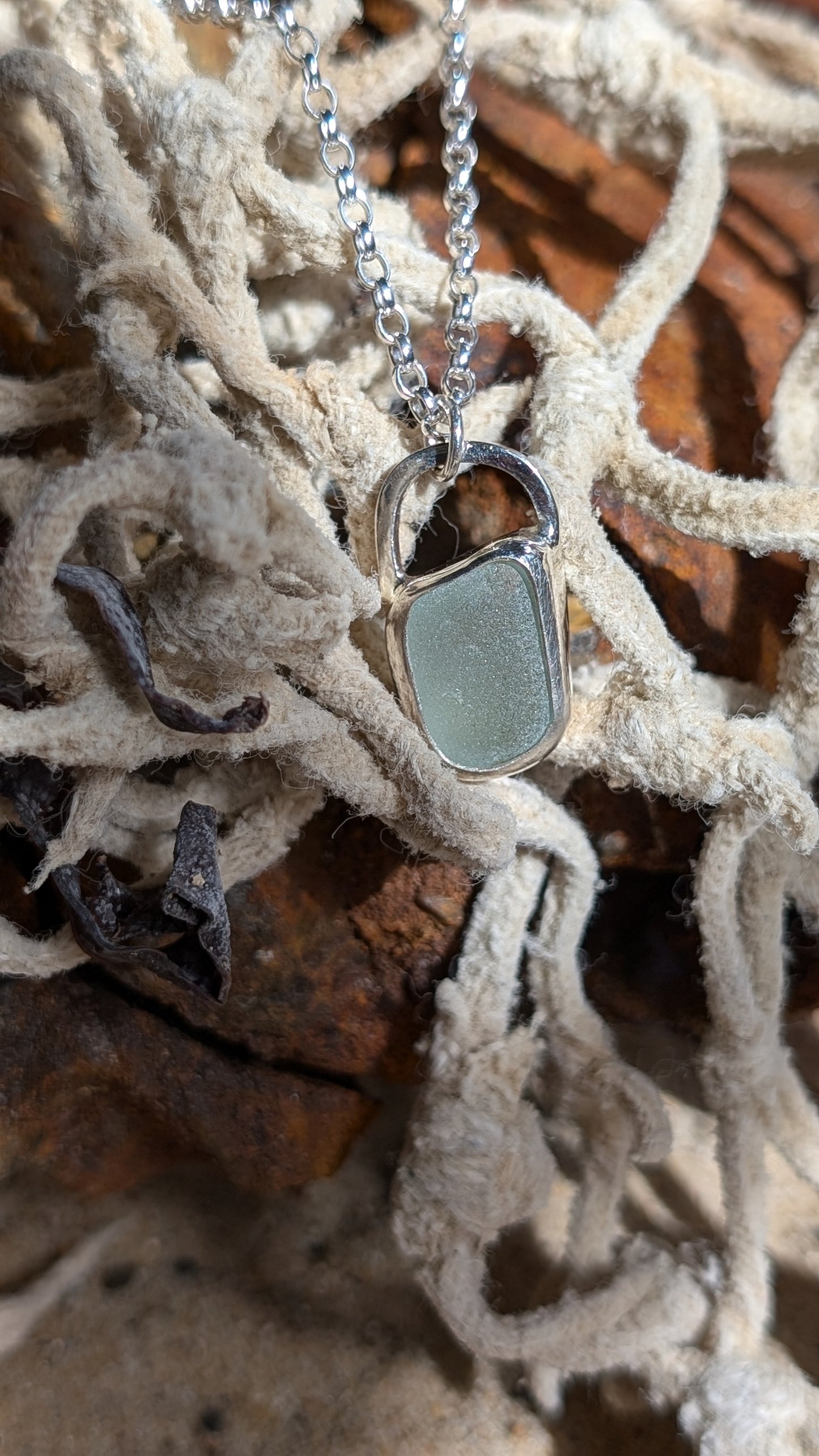 Sea foam sea glass pendant encased in open backed bezel with chain