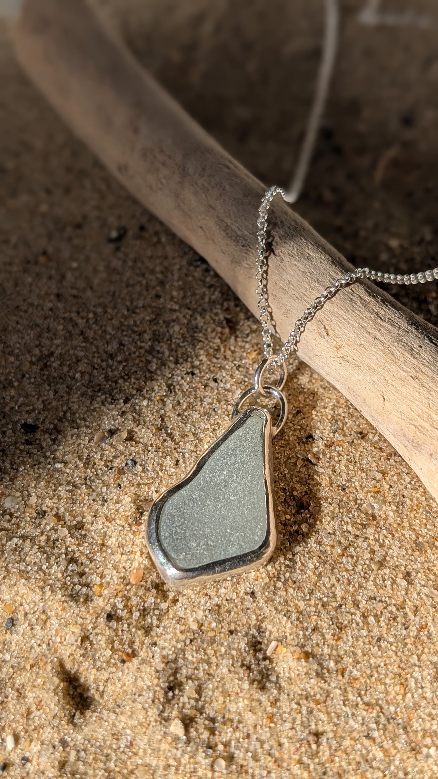 White sea glass pendant encased in open backed bezel with chain