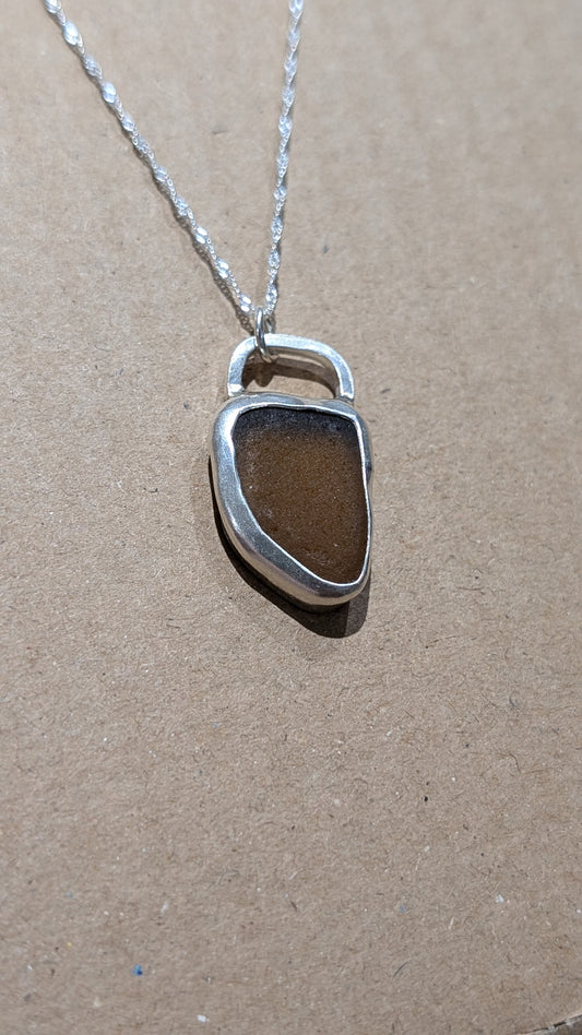 Brown sea glass pendant encased in open backed bezel with chain